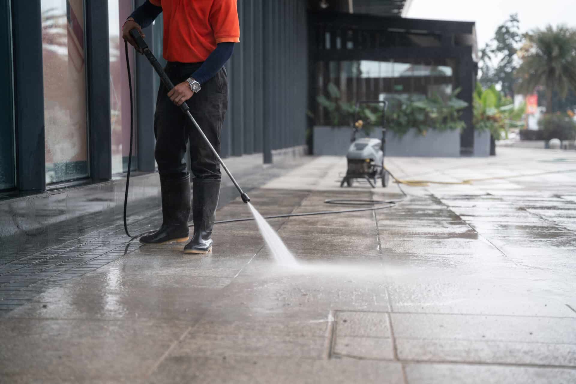 cleaning staff hoses a portable car for washing the concrete floor with high-pressure water jets.